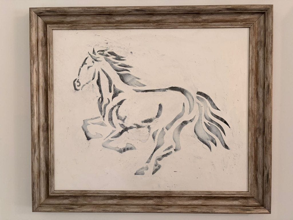 Rustic framed painting of a running horse in neutral tones.